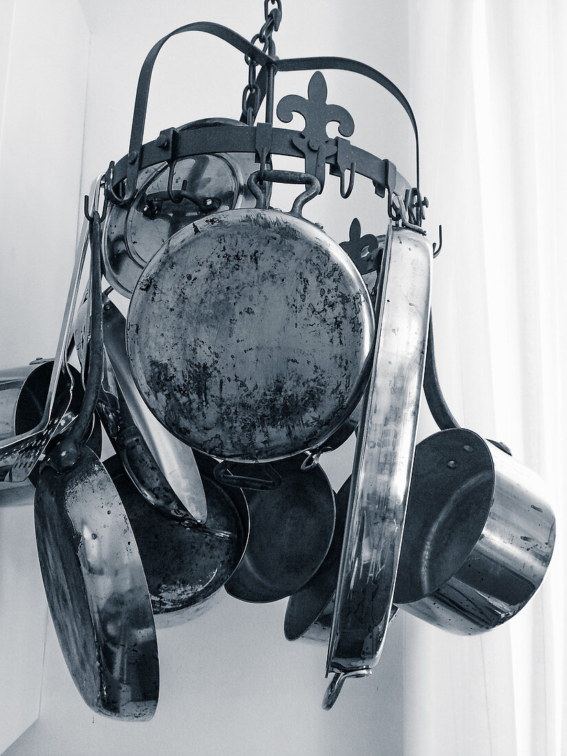 Old pots and pans on a hanging rack in a kitchen