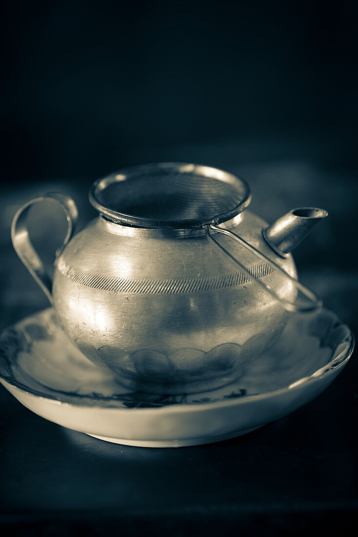 An old teapot with a tea strainer