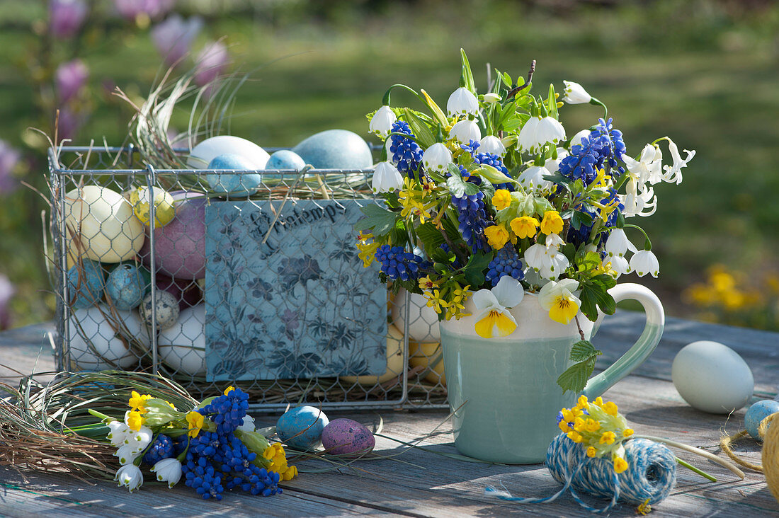 Colorful bouquet of grape hyacinths, spring cups, horned violets, cowslips, hyacinth and gold currants, wire basket with Easter eggs