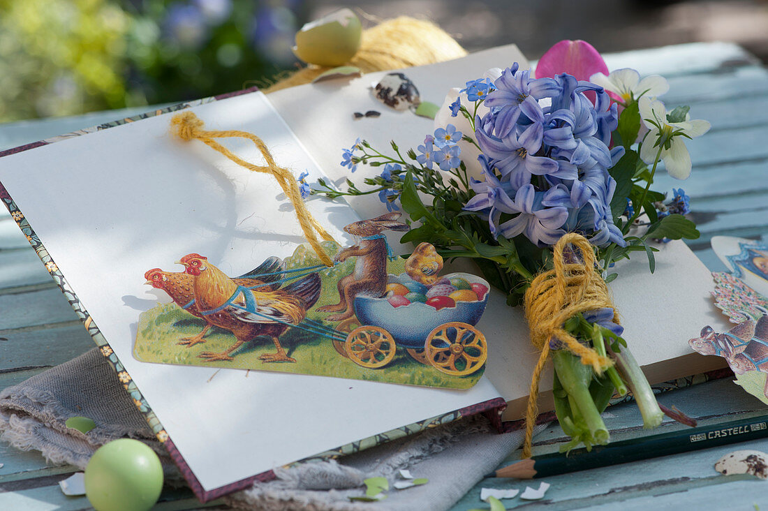Small bouquet of hyacinths, horned violets, forget-me-nots and tulips, glossy pictures with Easter bunny as decoration