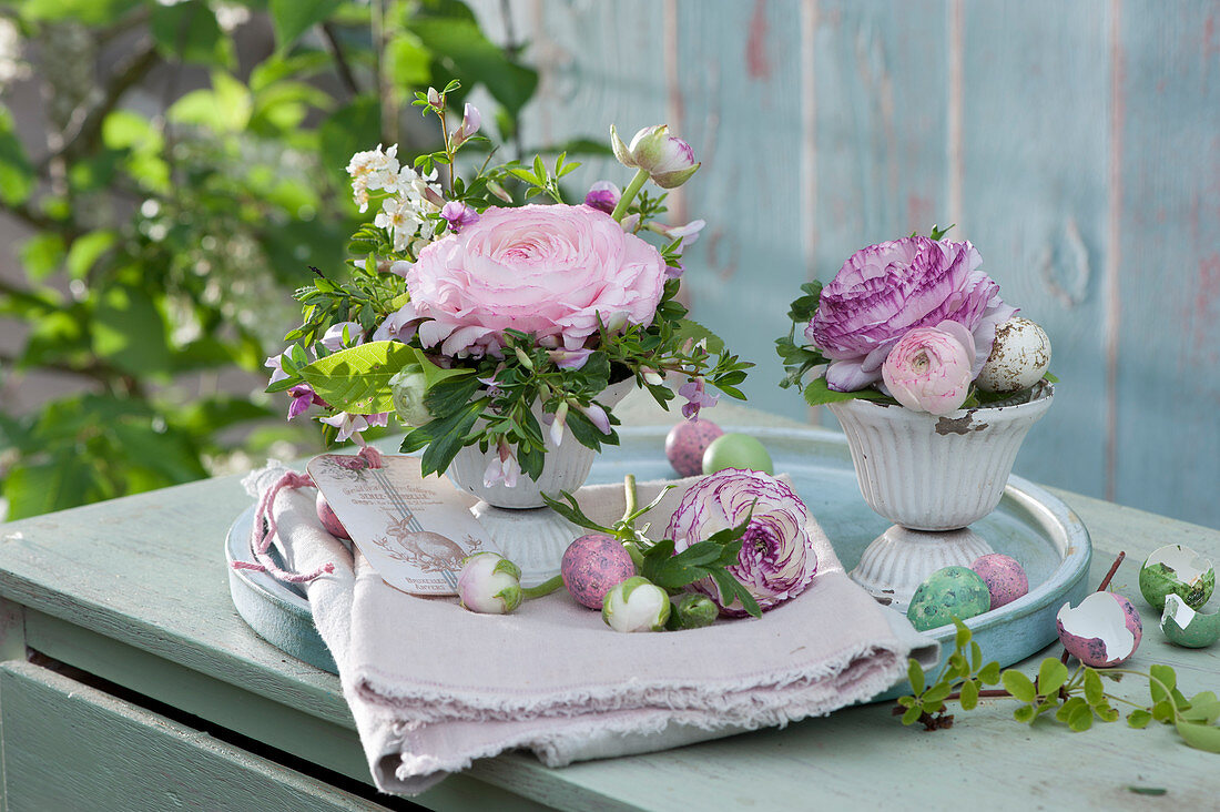 Small Easter decorations with ranunculus, rose broom and orange flower, Easter eggs and pendants as decoration