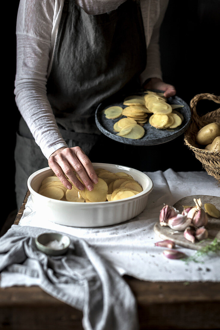 Kartoffelgratin zubereiten: Kartoffelscheiben in Form schichten