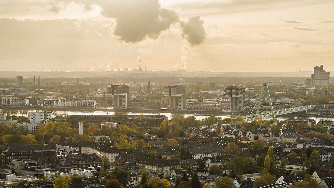 Blick auf Köln, im Hintergrund Rauch steigt aus den Fabriken auf