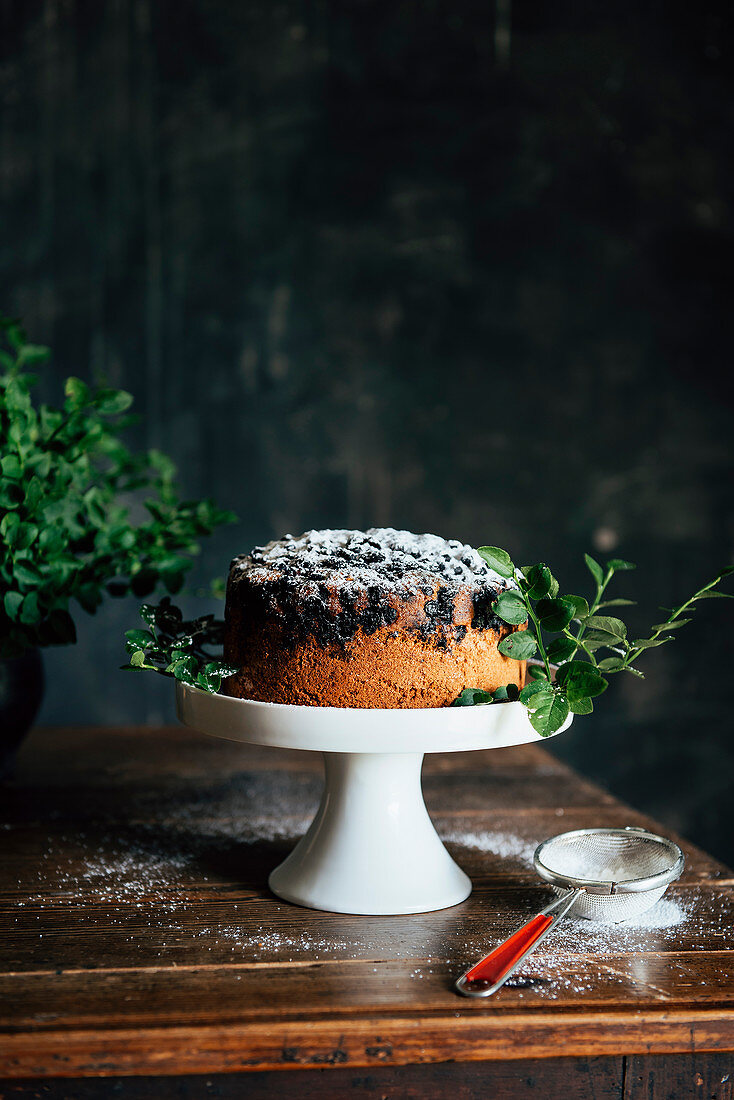 Blaubeerkuchen mit Puderzucker auf Kuchenständer