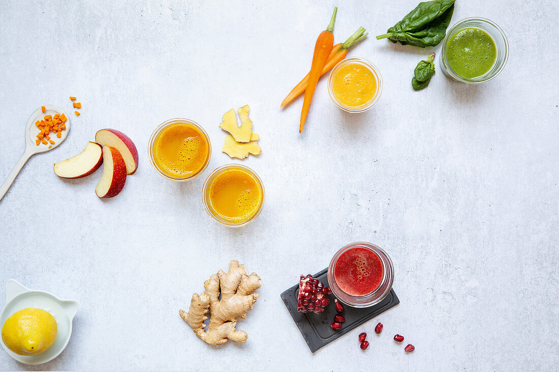 Colourful ginger shots made with apple, carrots, spinach and pomegranate seeds