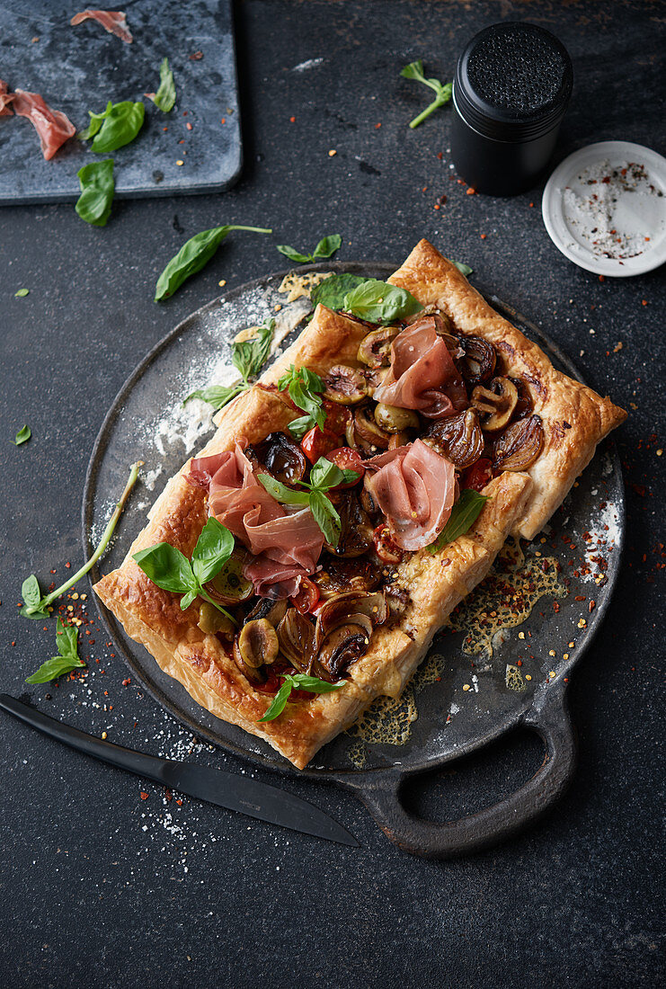 Puff pastry tart with Parma ham, balsamic onions, tomatoes, cheese, mushrooms and olives