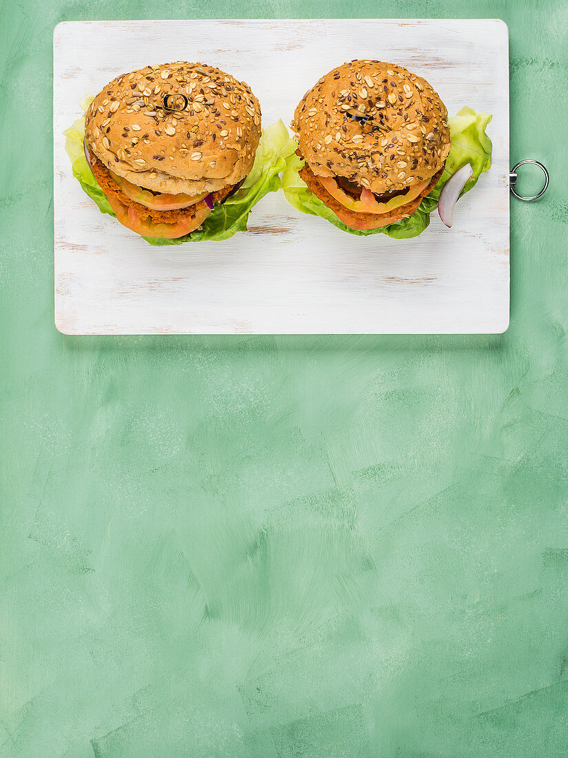 Veganer Burger: Dinkelbrötchen mit Soja-Gemüse-Patty, Salatblatt, Tomate und roten Zwiebeln