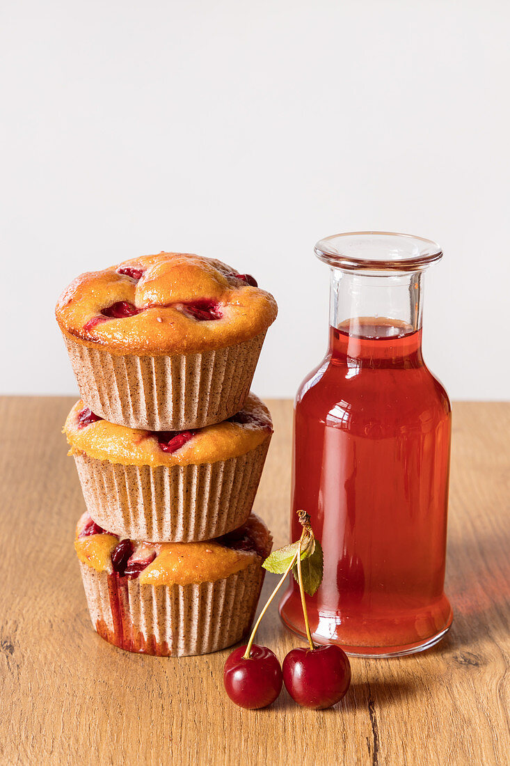Freshly baked cherry muffins and bottle of stewed fruits drink