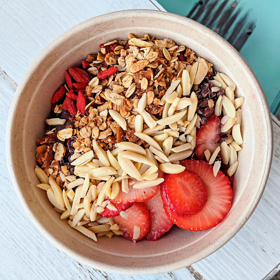 Breakfast bowl with granola, banana, goji berries, almonds and strawberries