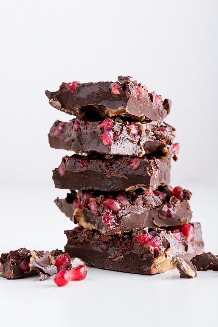 Homemade chocolate bars with peanut sauce and pomegranate seeds