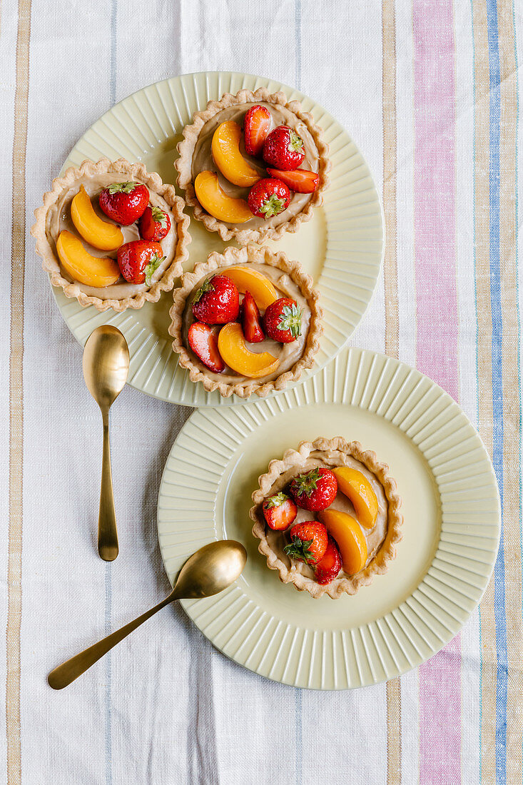Fresh fruit tarts with caramel chocolate ganache, strawberries and apricots