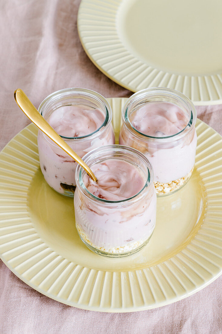 Cherry yogurt with granola and agave syrup in glass jars