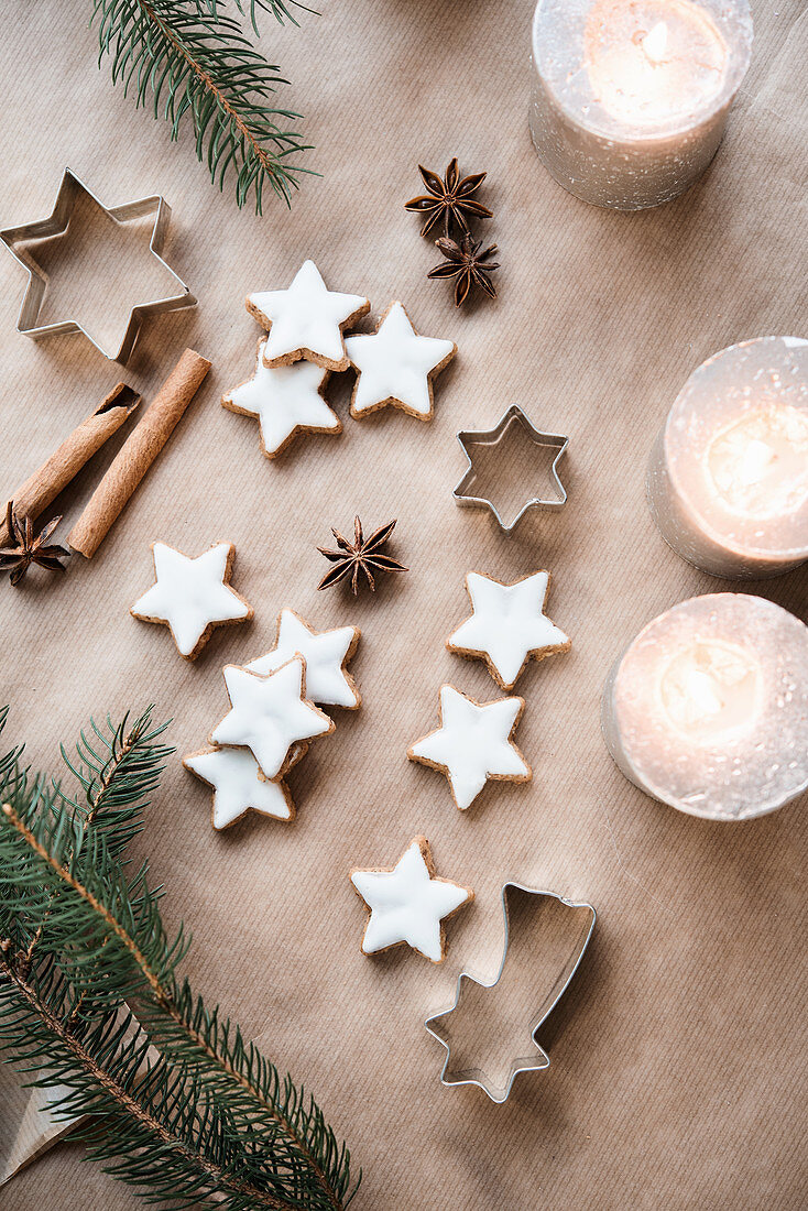 Cinnamon stars next to burning candles and fir tree branches