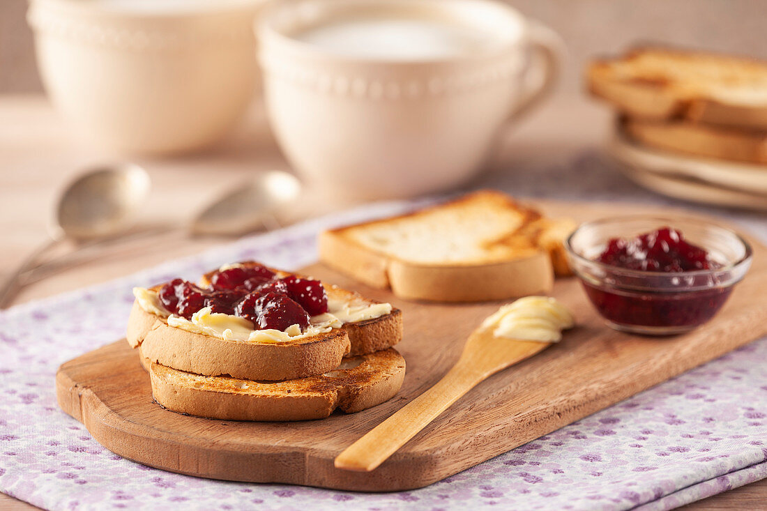Toast mit Butter und Erdbeermarmelade auf Frühstücksbrett