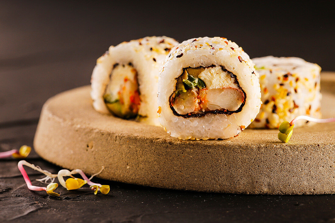 Sushi rolls filled with shrimp and cream cheese, covered with sesame seeds.