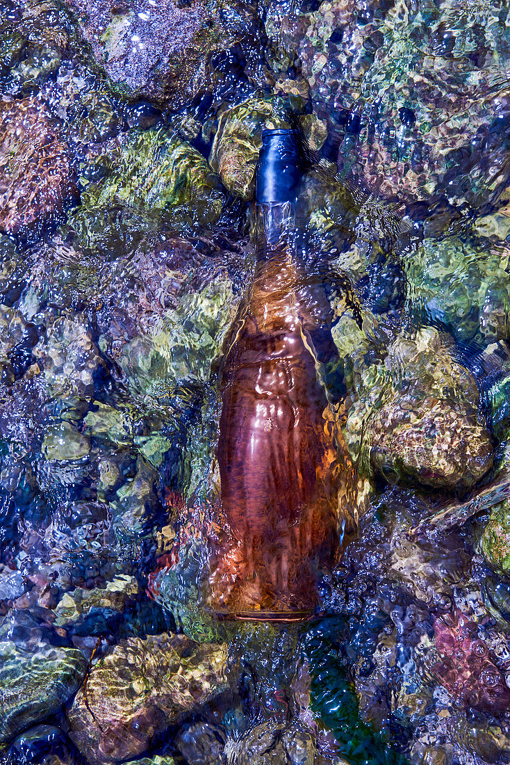 A bottle of rose wine in flowing water