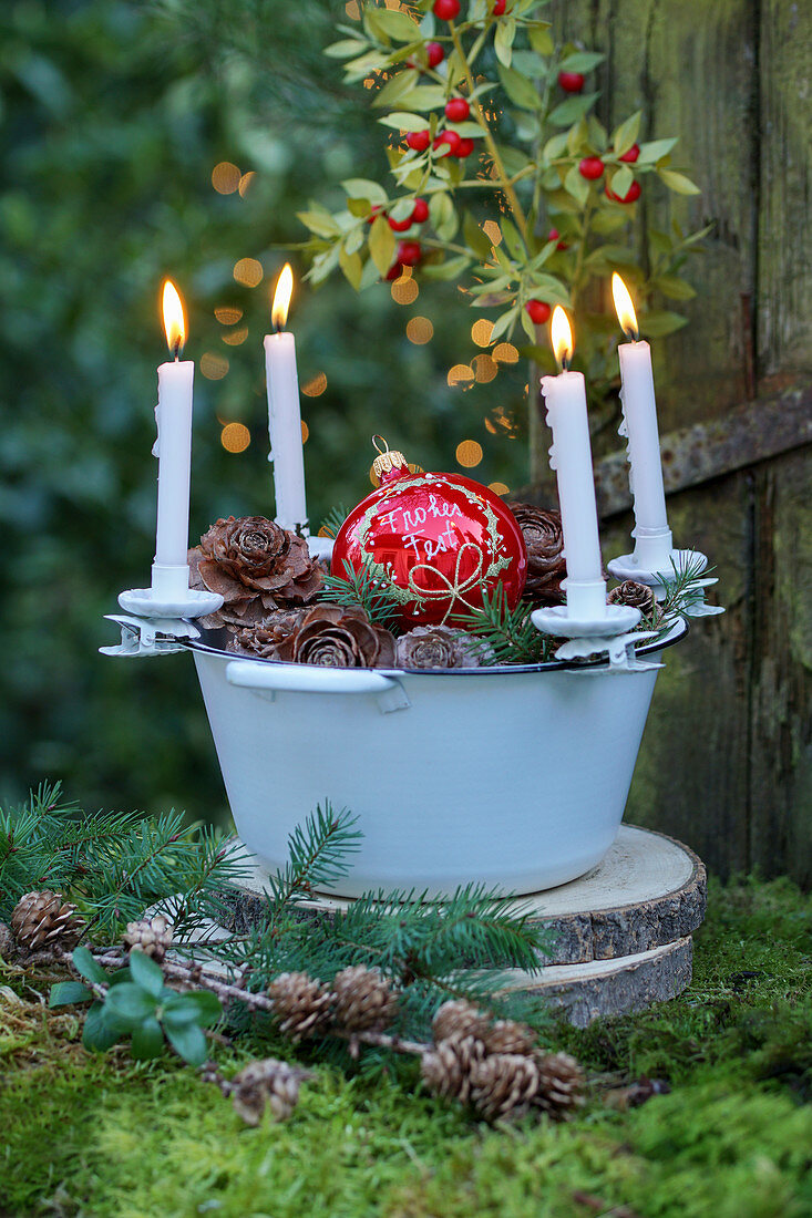 Adventskranz mit Kerzenhaltern an einer Emailleschüssel im Freien