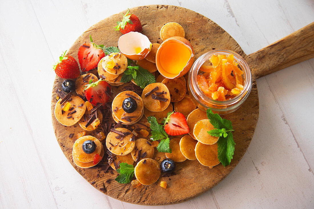 Minipancakes with siroup, strawberries, blueberries, candied orange and chocolate