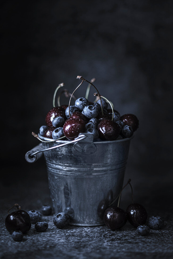 Blaubeeren und Kirschen in einem Zinkeimer