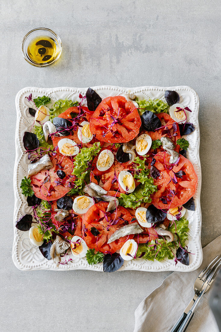 Salad made with anchovies, quaileggs, tomatoes, amarantus, lettuce and purple basil