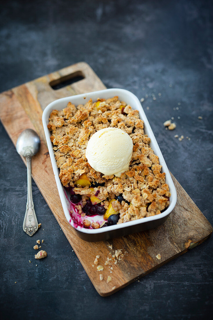 Vegan crumble with peaches, blueberries and oat flakes