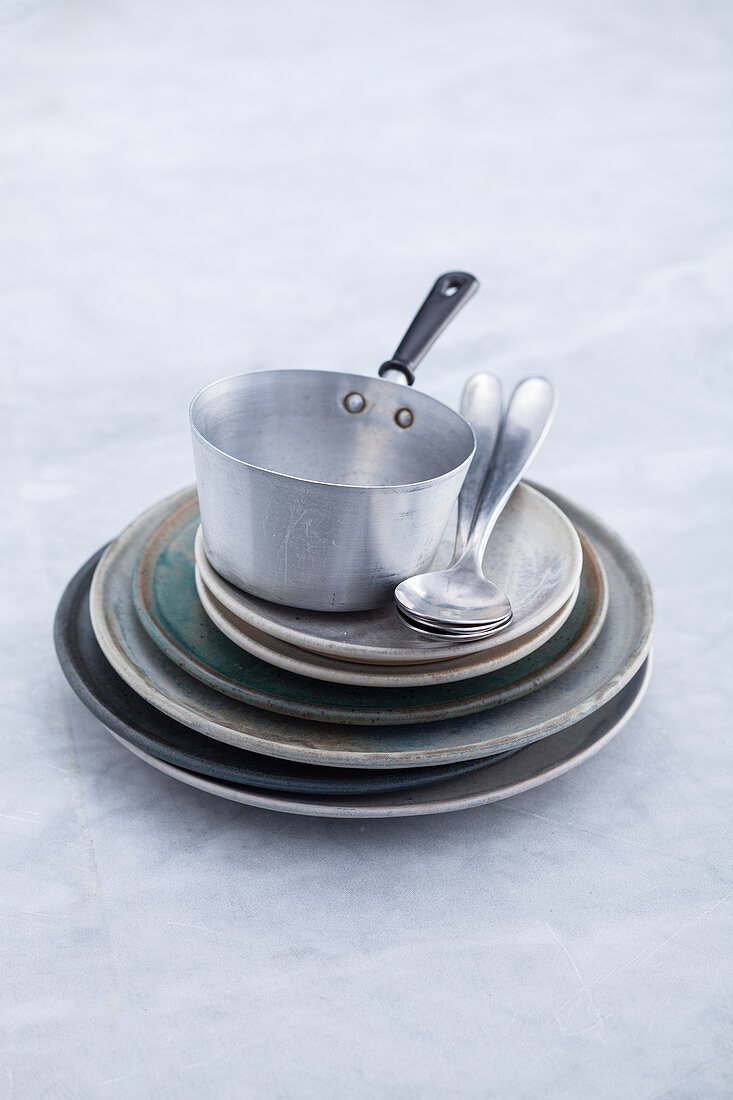 Plates of various sizes, a saucepan and dessert spoons