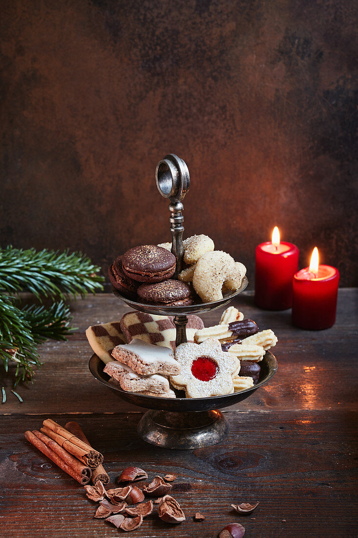 Various Christmas biscuits on a cake stand by candlelight