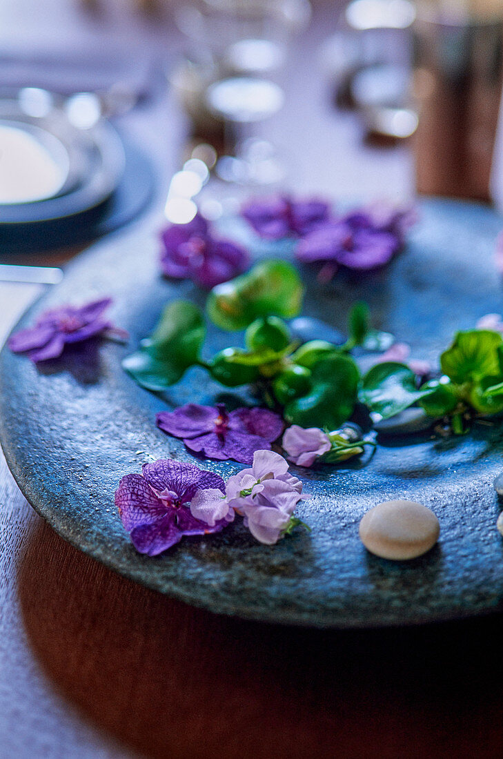 Lila Blüten auf Steinteller als Tischdeko