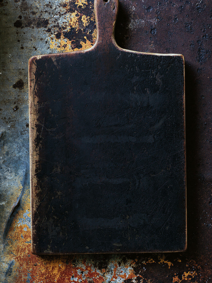 A dark wooden chopping board on a metal surface