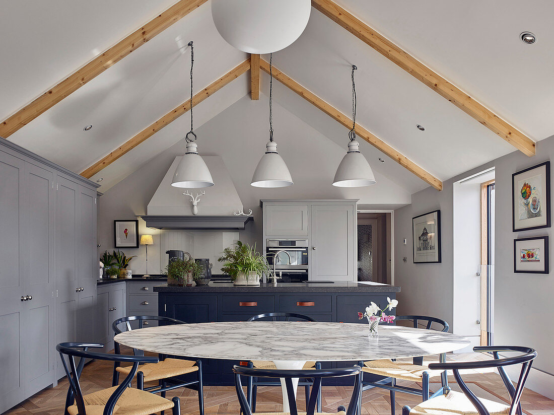 Large, round marble dining table and open-plan kitchen in living space on gallery