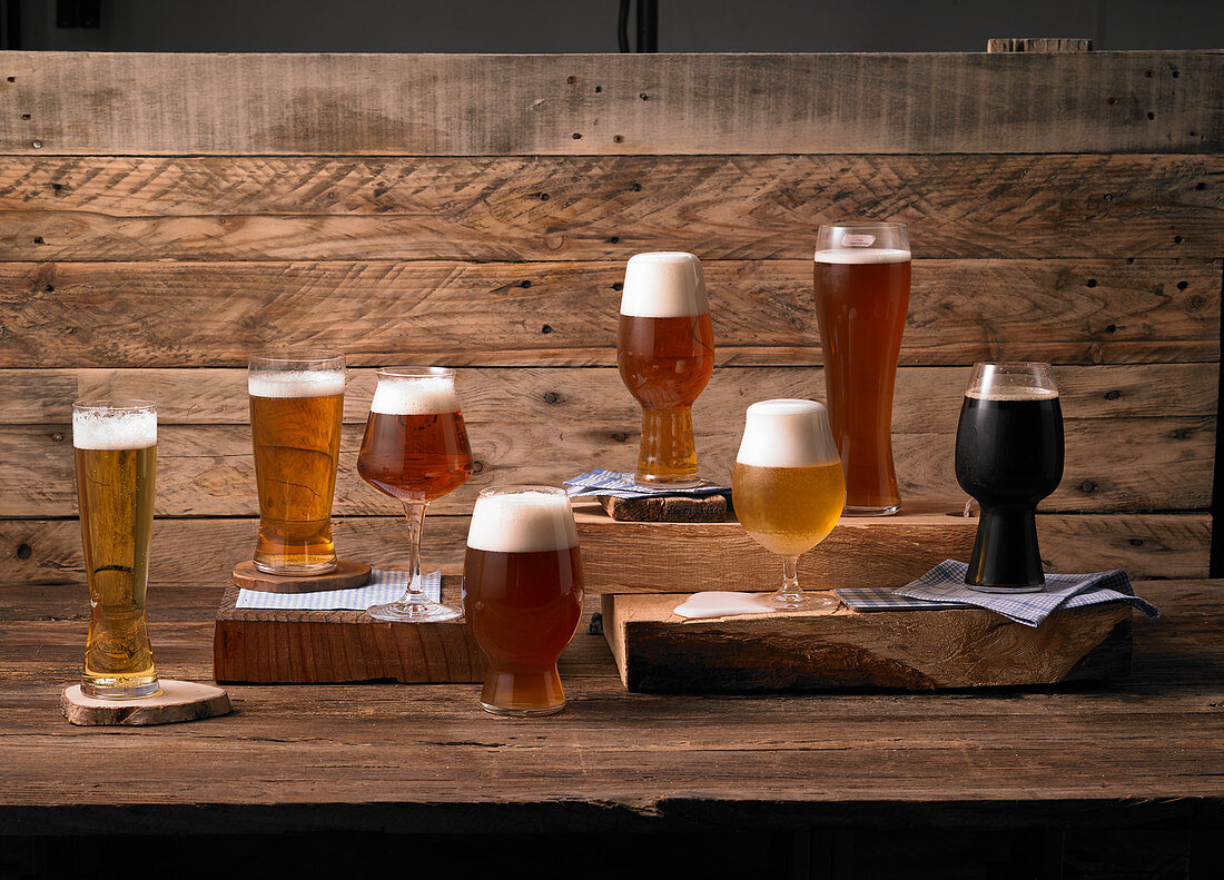 Various glasses of beer against a wooden background