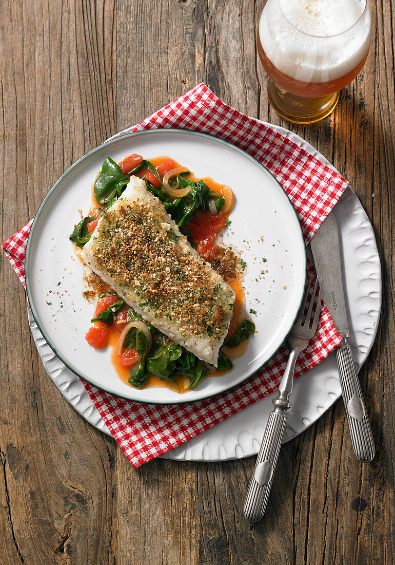 Wolf-fish fillet with a crispy garlic and herb crust on a bed of spinach