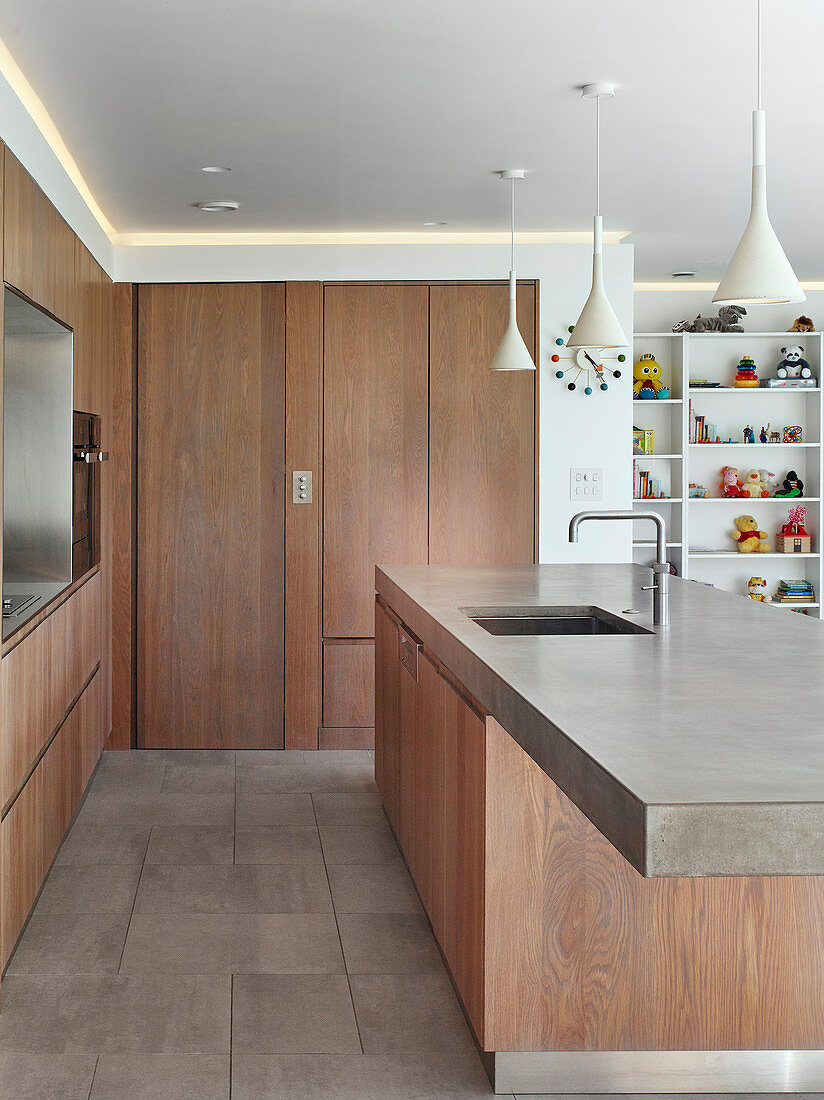 Designer kitchen with wooden cabinets and concrete worksurface on island counter