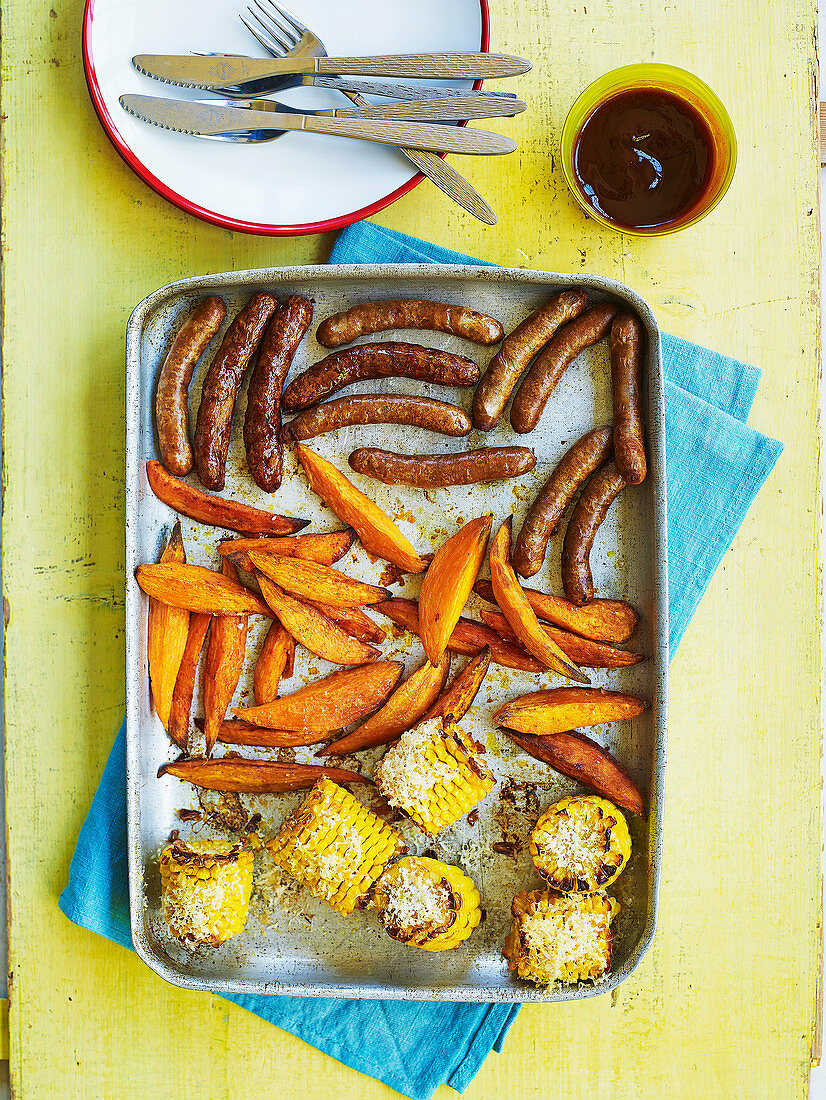 Würstchen, Süßkartoffeln und Maiskolben aus dem Ofen