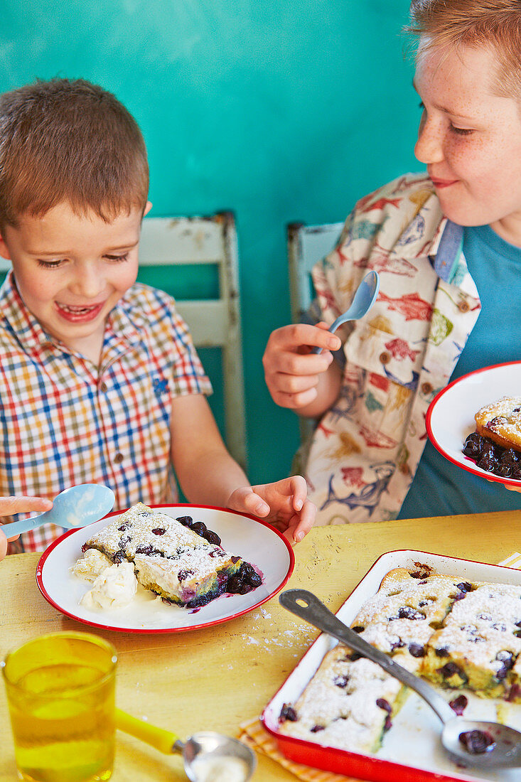 Children eating blueberry and orange traybake pancake