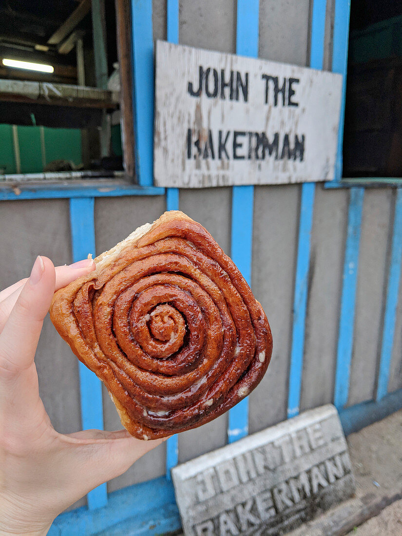 Hand hält Zimtschnecke in Placencia, Belize