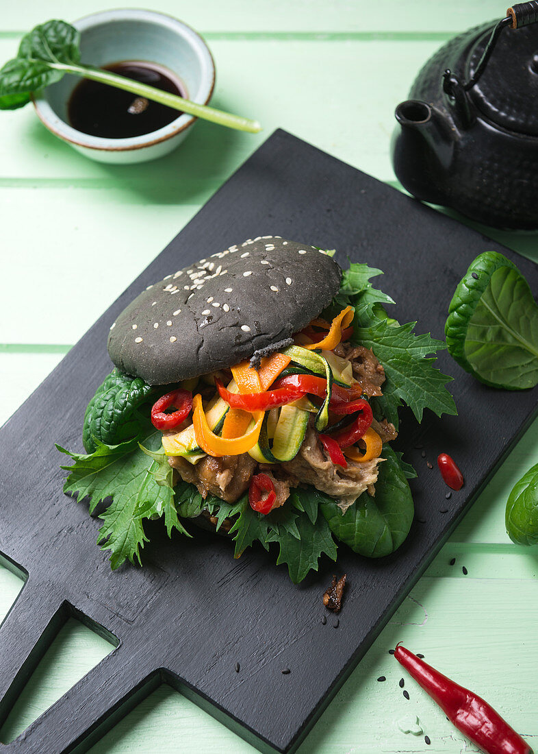 Veganer schwarzer Burger mit Mock Duck, Asiasalat und Grillgemüse