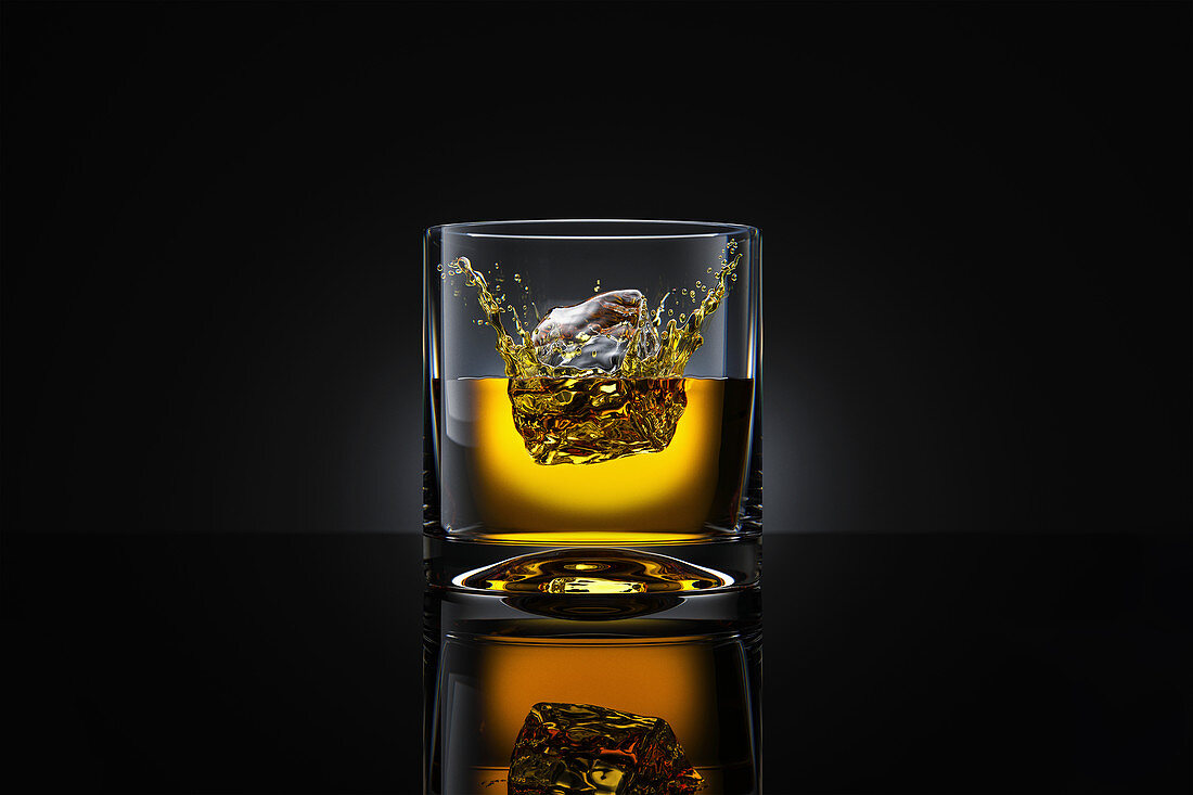 Eiswürfel fällt in Whiskeyglas