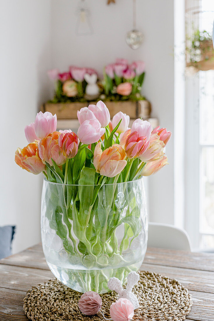 Vase of pink and apricot tulips on table in dining room