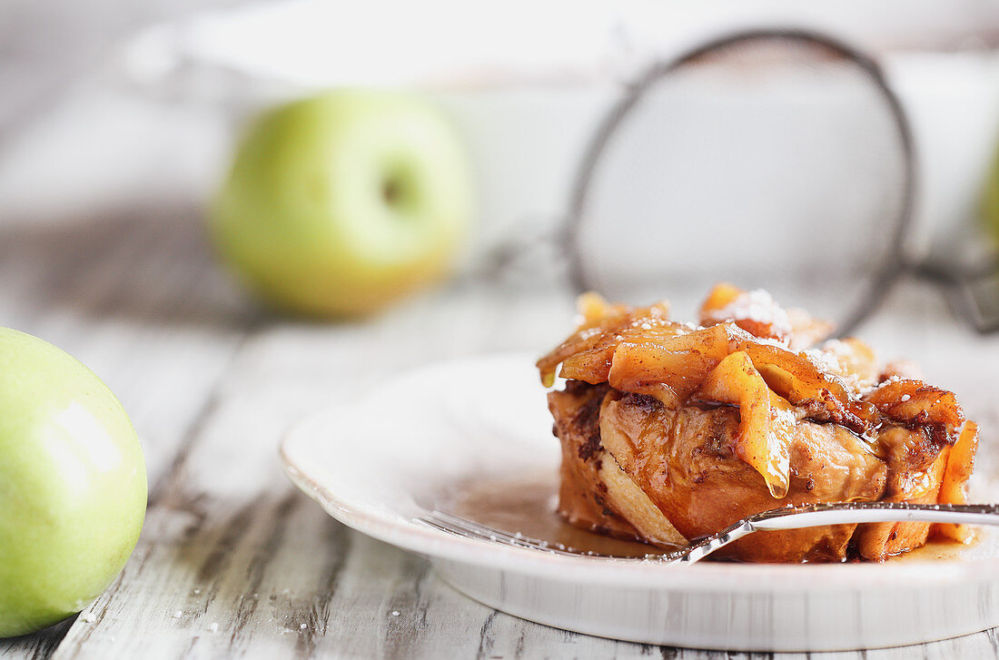Apple French toast casserole with maple syrup and powdered sugar