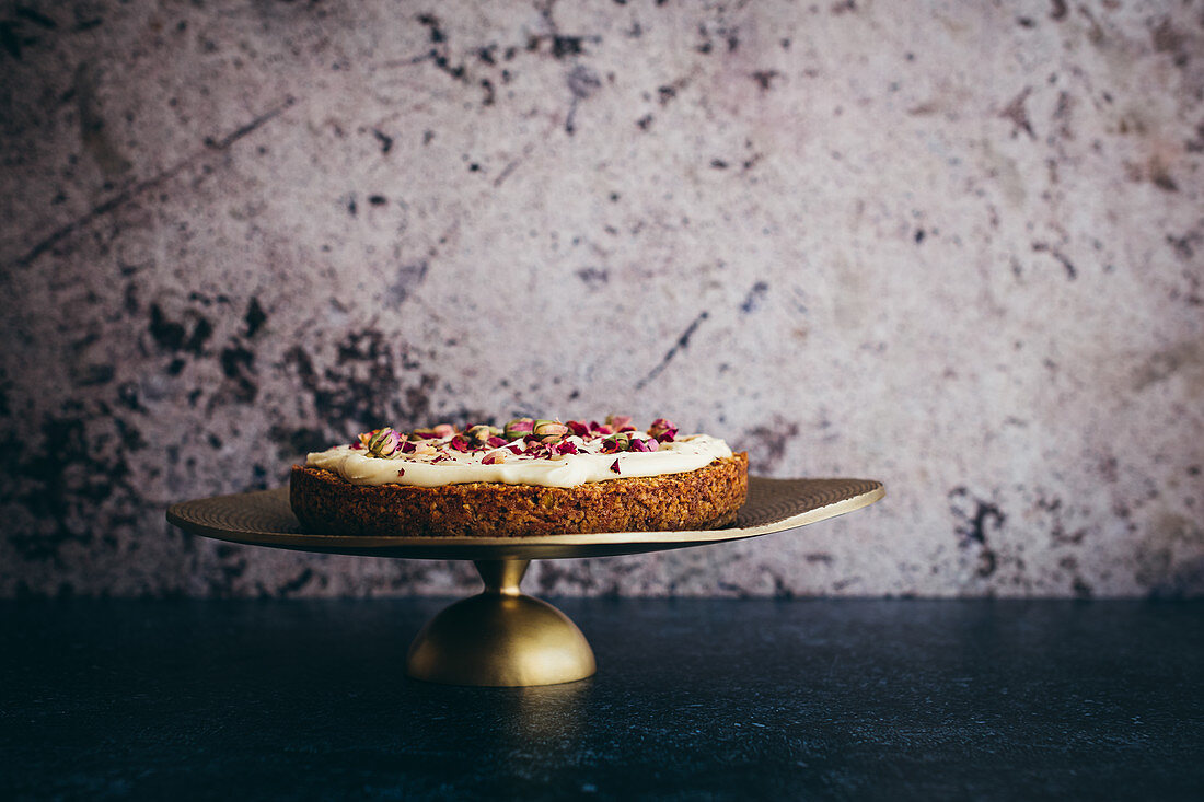 Gluten-free carrot cake with tahini glaze and rose petal decoration