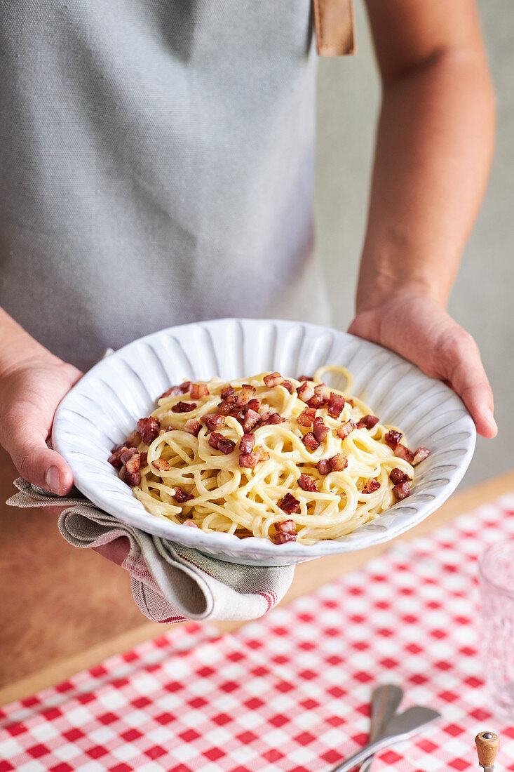 Frau serviert Spaghetti Carbonara