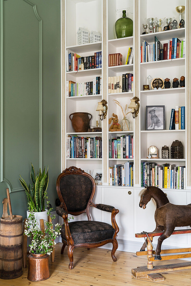 Floor-to-ceiling shelving, antique chair and rocking horse in living room