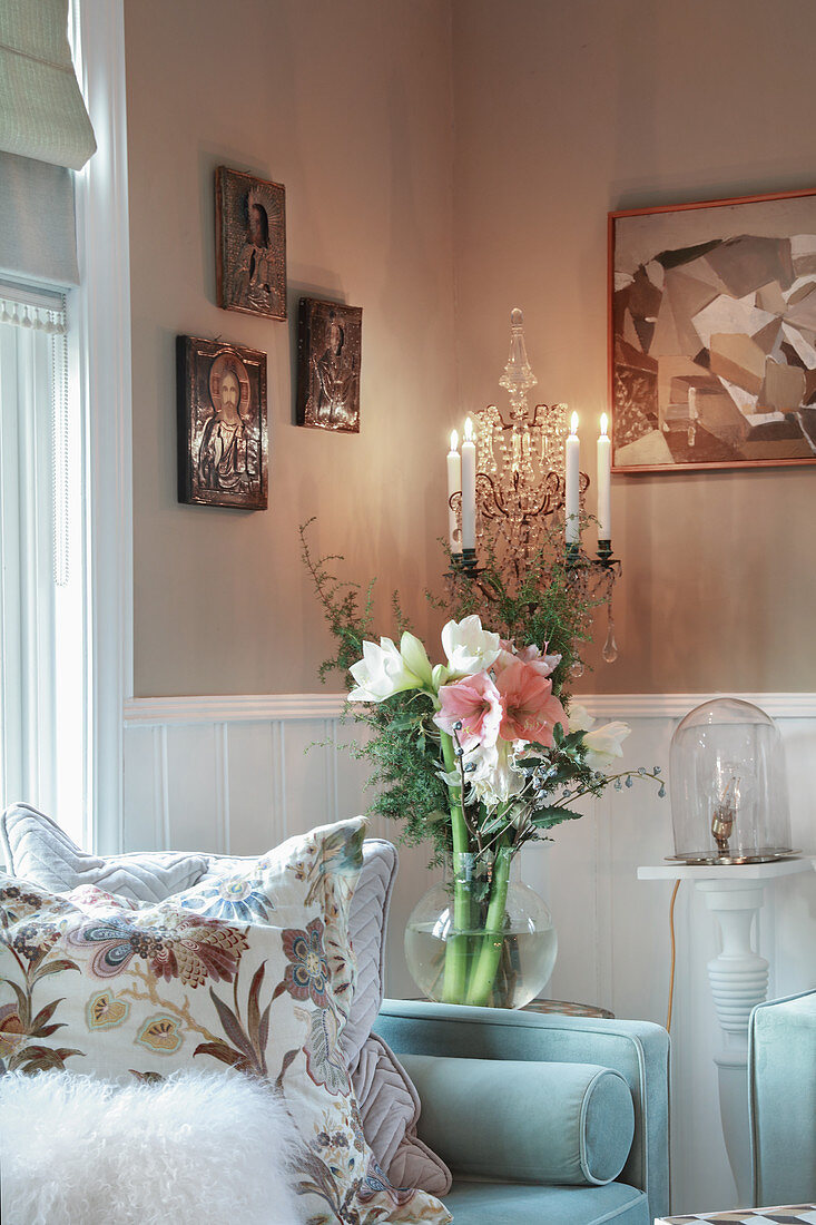 Hellblaues Sofa mit Kissen, daneben Glasvase mit Blumenstrauß