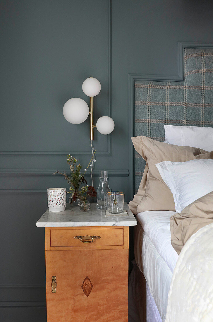 Bedside table with marble top against blue wall in bedroom