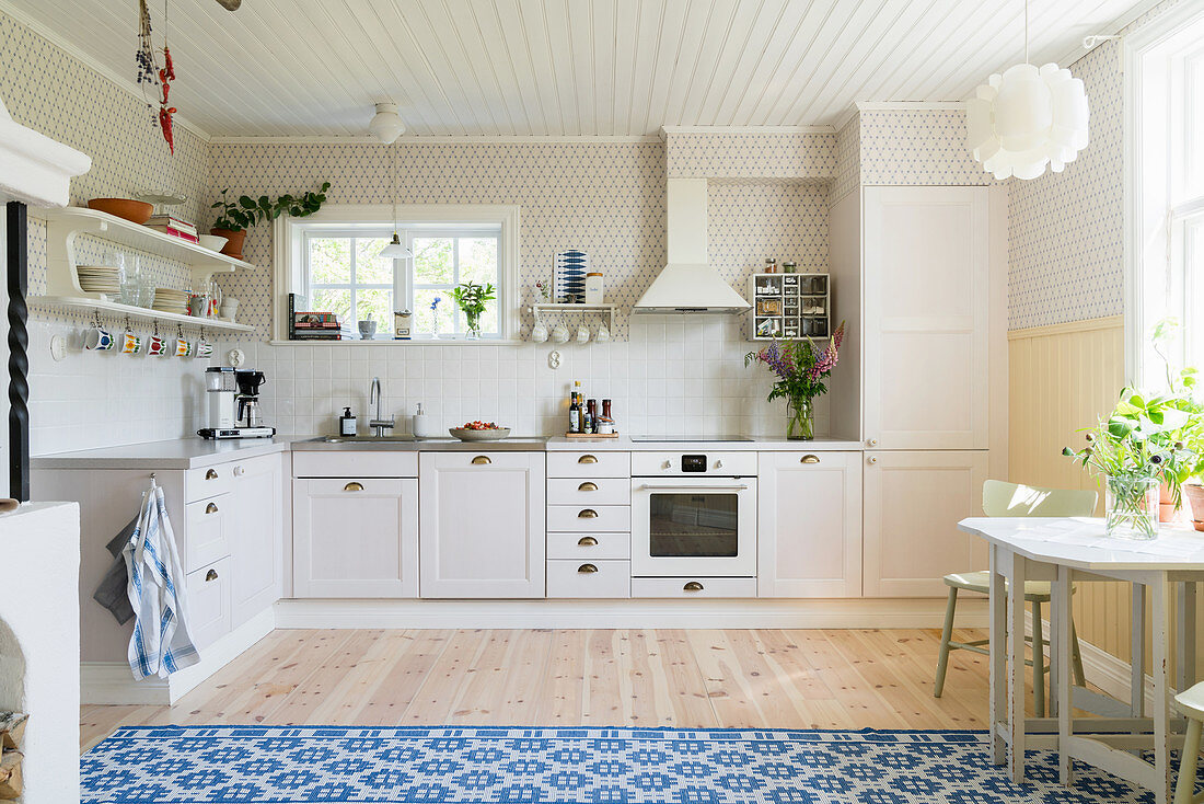 Helle Küche mit Holzdielenboden und blau-weißem Teppich