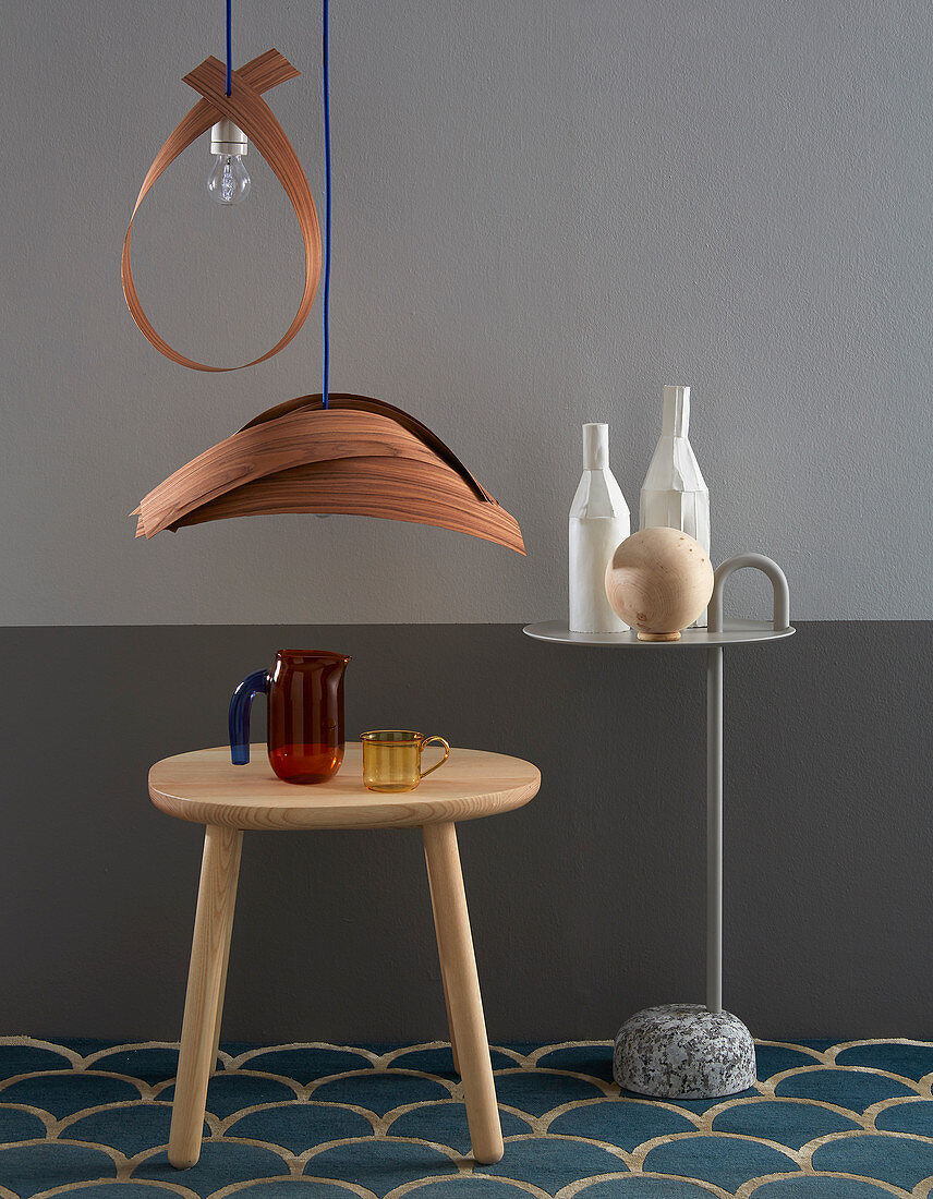 Lampshades made from wooden veneers above side table in front of grey wall