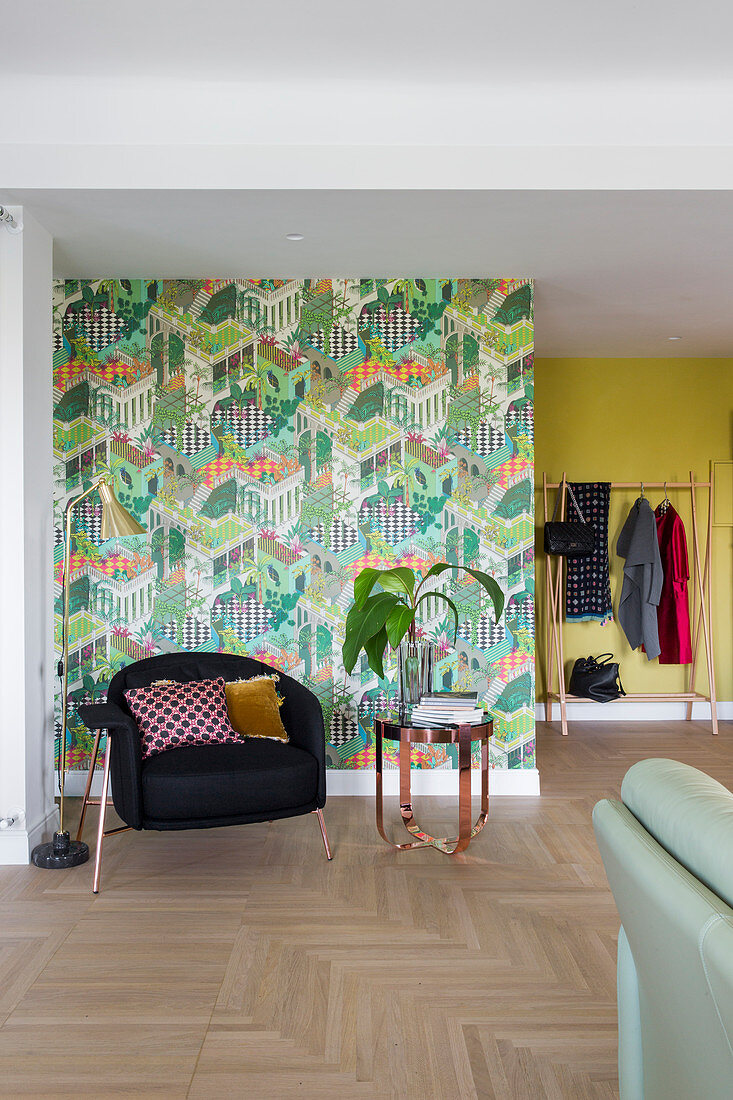 Black armchair against green-patterned retro wallpaper