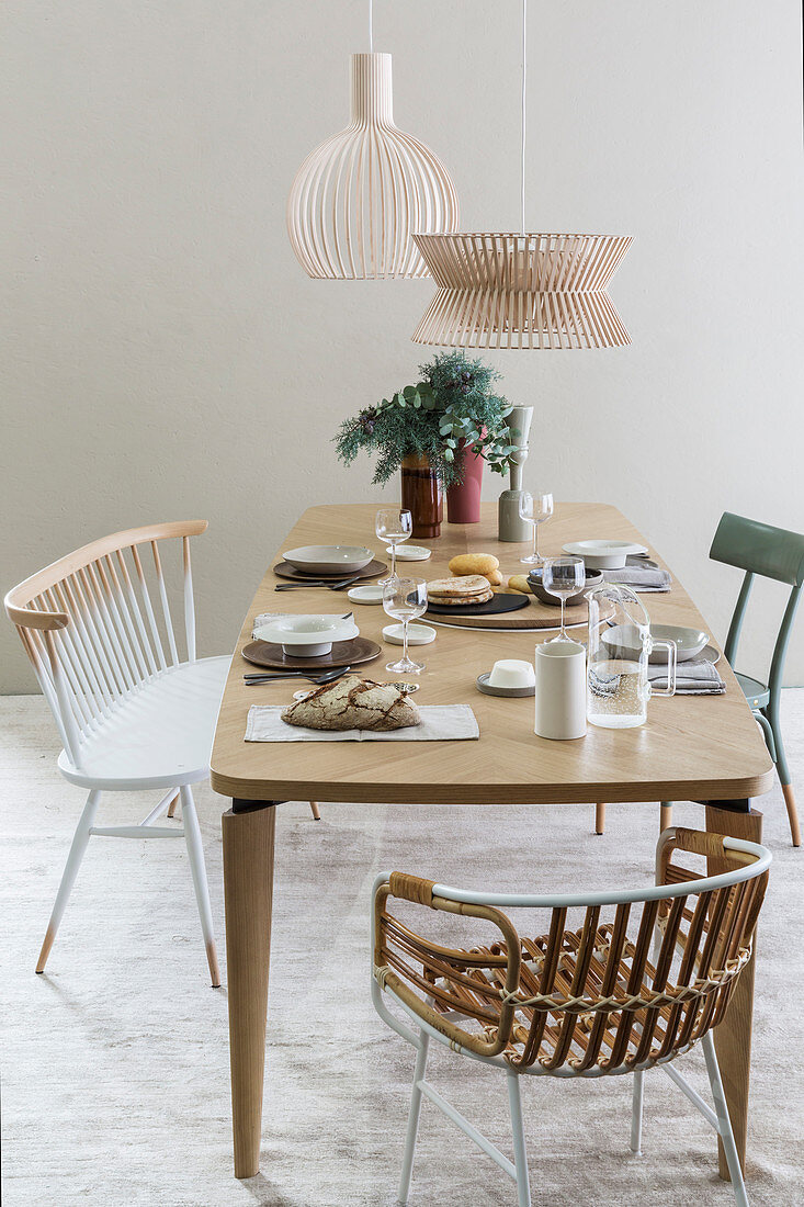 Gedeckter Tisch mit verschiedenen Stühlen im Esszimmer in Beige