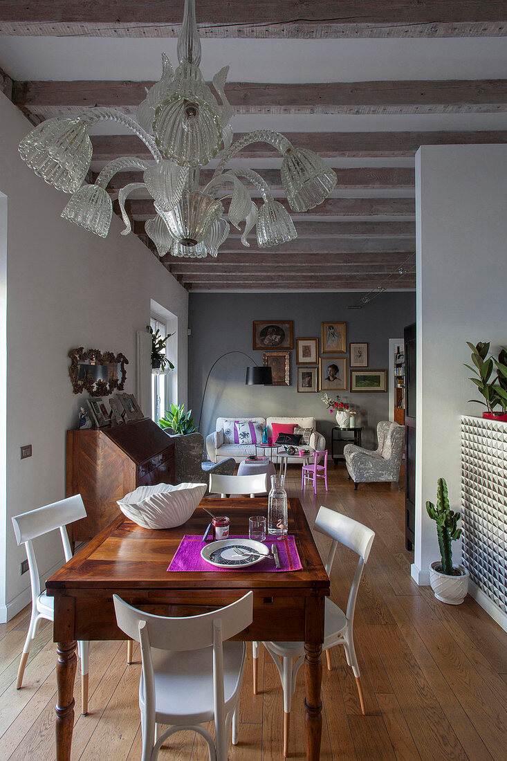 View past dining table and antique chandelier into open-plan living room